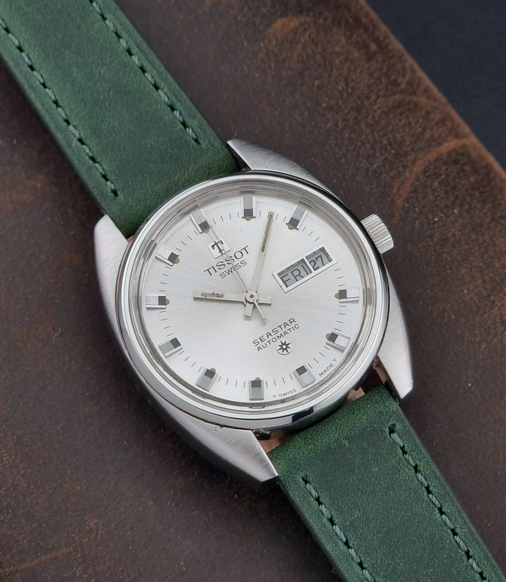 Tissot Seastar 46660 watch with green strap on a dark brown background