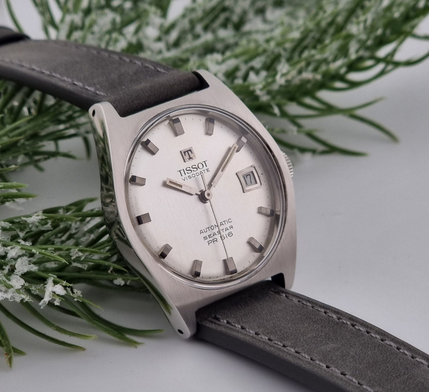 Vintage Tissot Seastar Visodate 43516 wristwatch with grey leather strap on a snowy branch background side view
