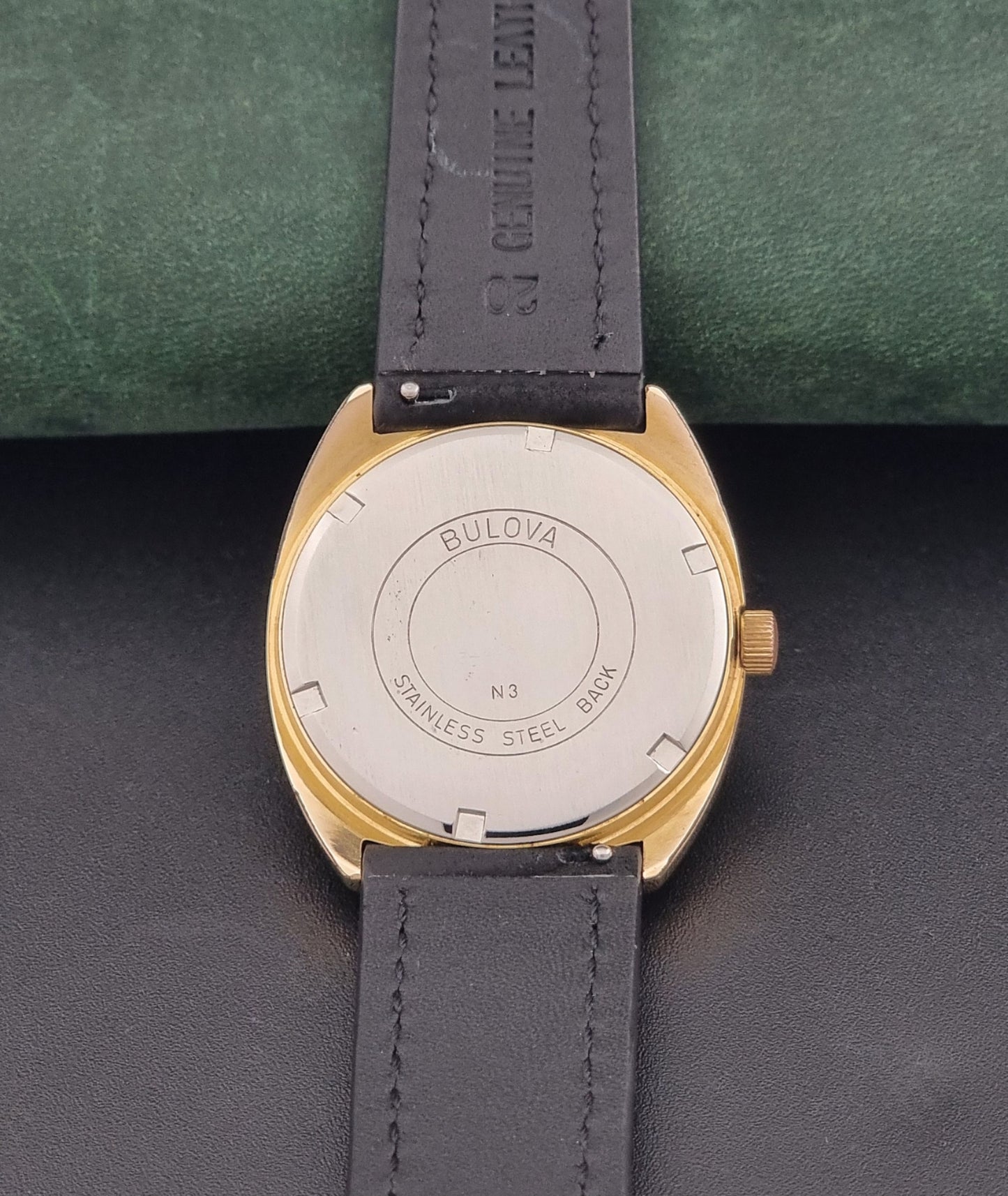 Vintage Bulova wristwatch 7530-1 with black leather strap on a gray surface case back view