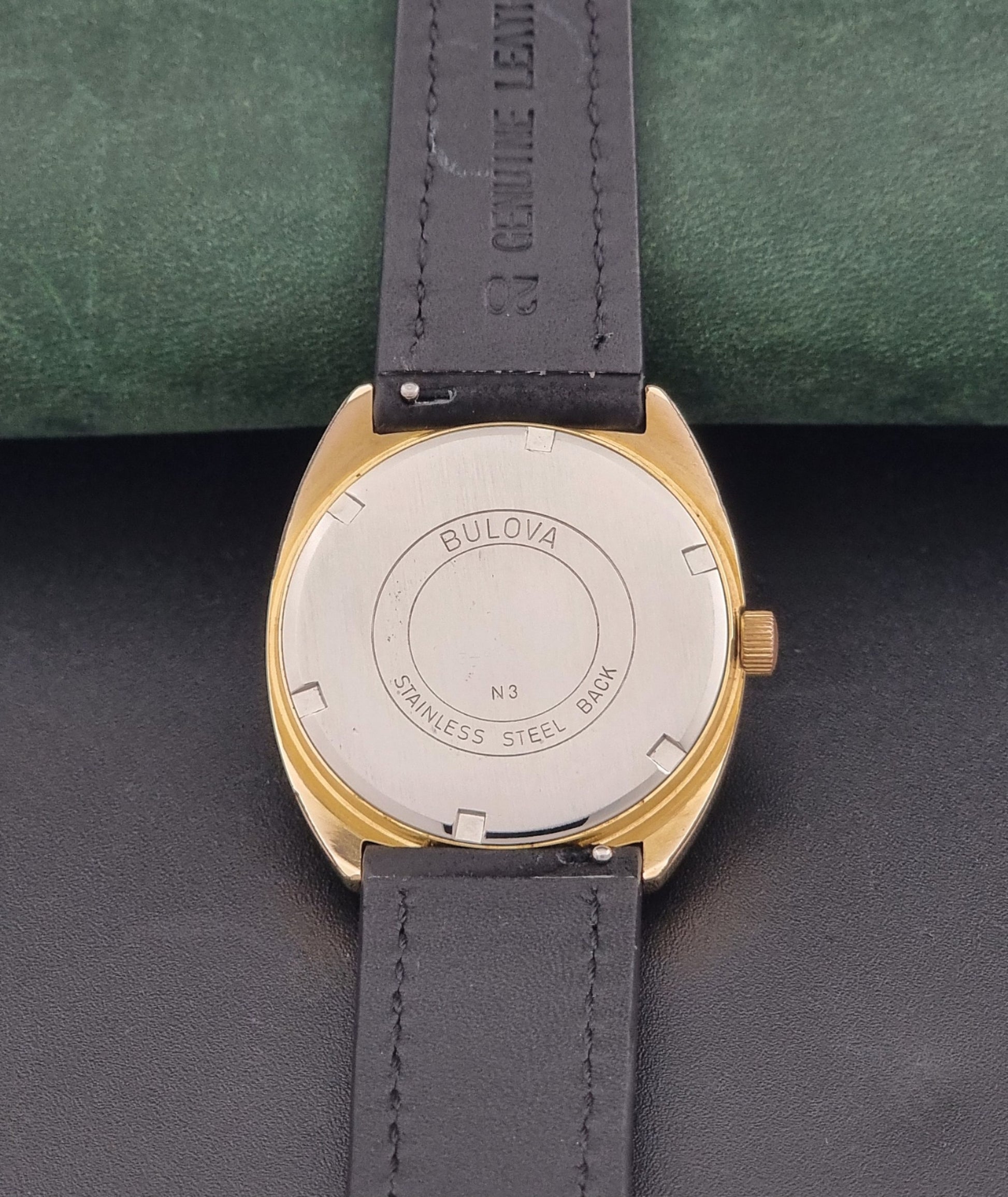 Vintage Bulova wristwatch 7530-1 with black leather strap on a gray surface case back view