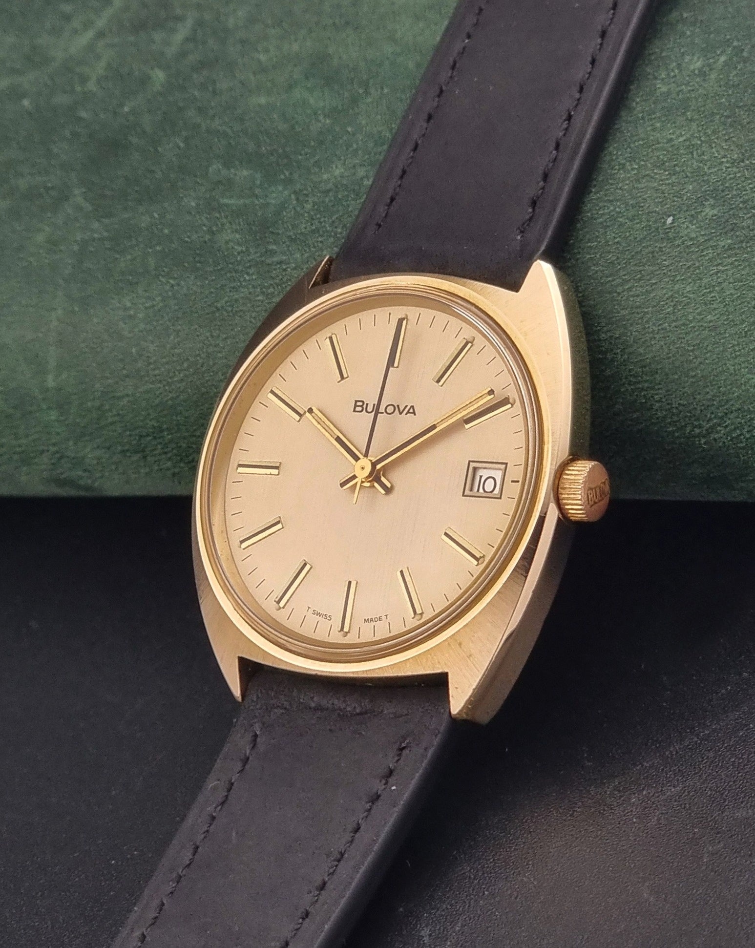 Vintage Bulova wristwatch 7530-1 with black leather strap on a gray surface crown view