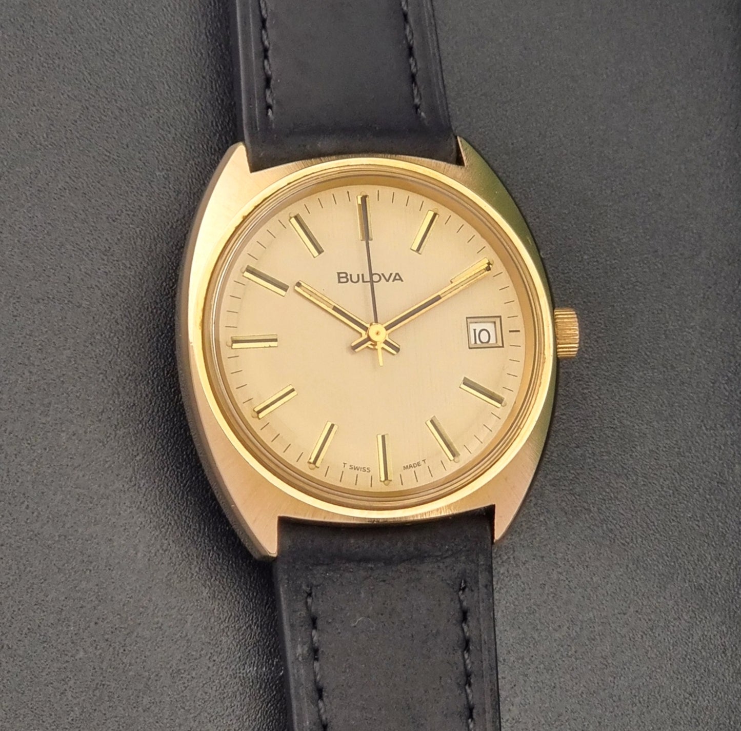 Vintage Bulova wristwatch 7530-1 with black leather strap on a gray surface front view