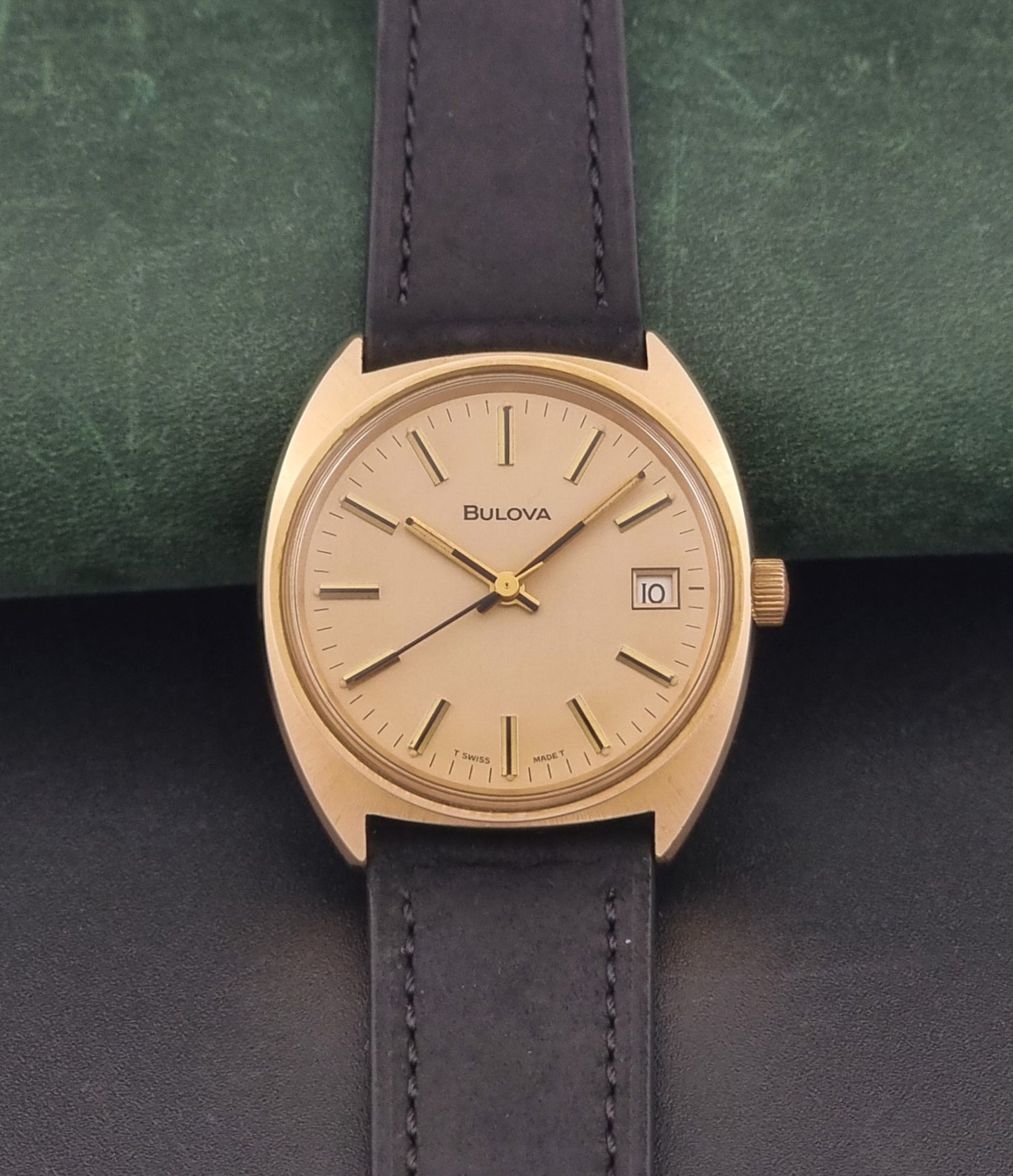 Vintage Bulova wristwatch 7530-1 with black leather strap on a gray surface dial view