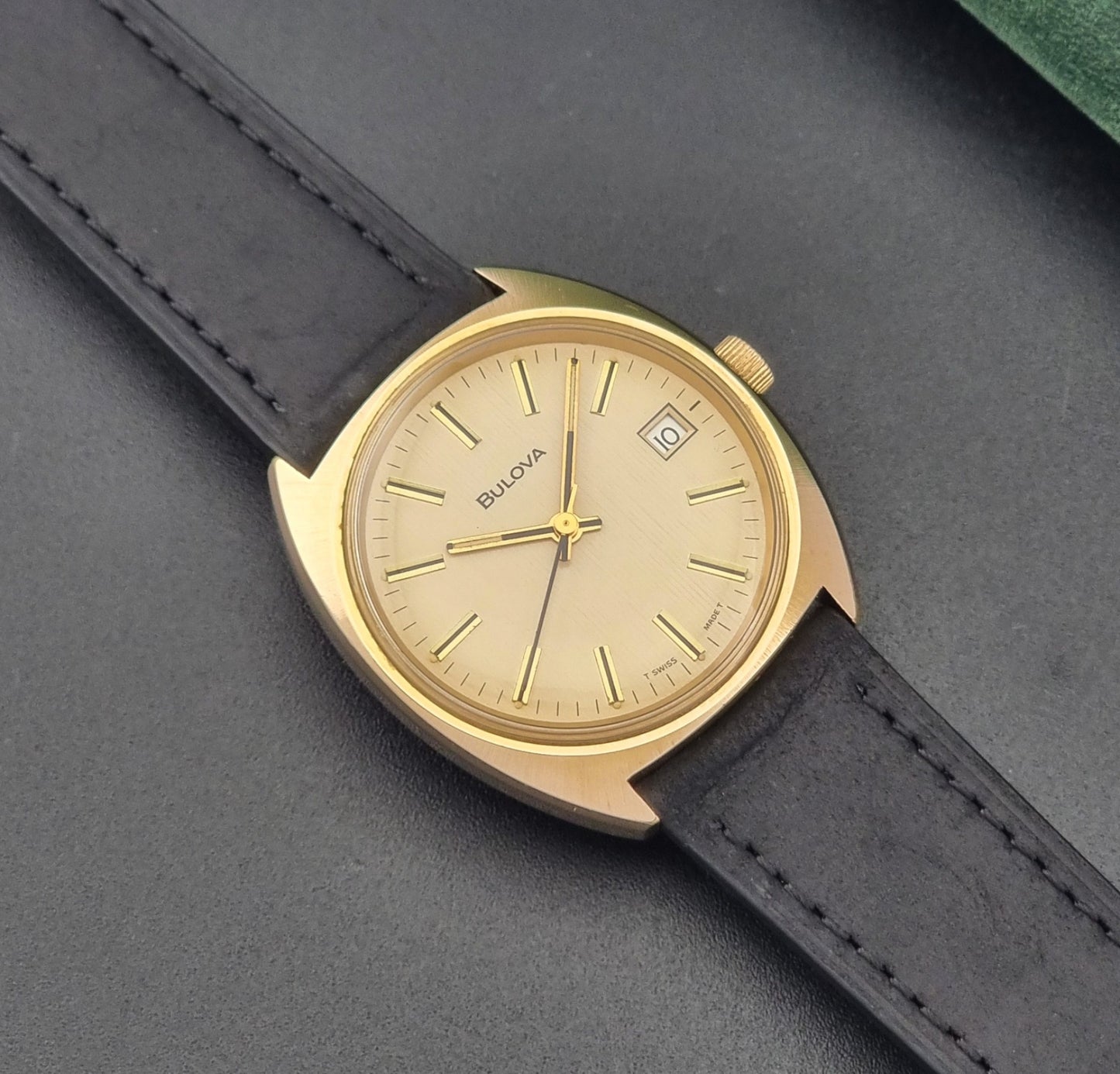 Vintage Bulova wristwatch 7530-1 with black leather strap on a gray surface close up dial view