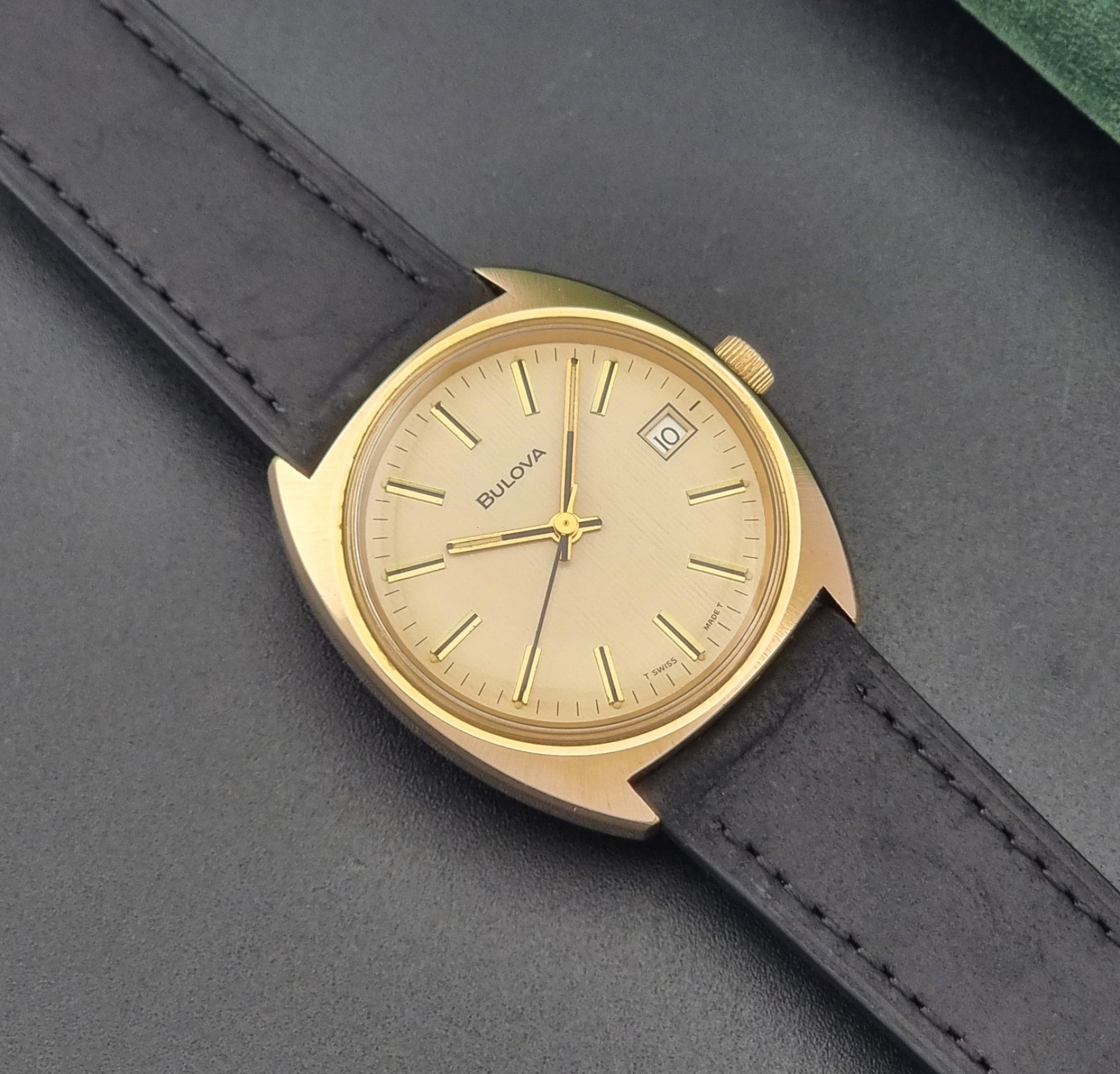Vintage Bulova wristwatch 7530-1 with black leather strap on a gray surface close up dial view