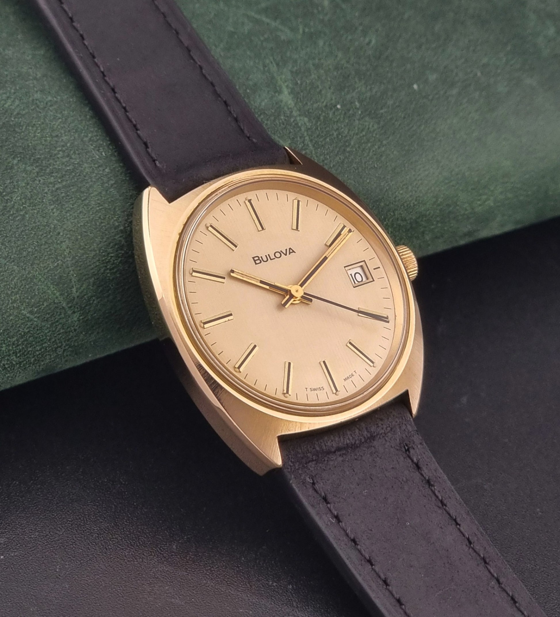 Vintage Bulova wristwatch 7530-1 with black leather strap on a gray surface side view