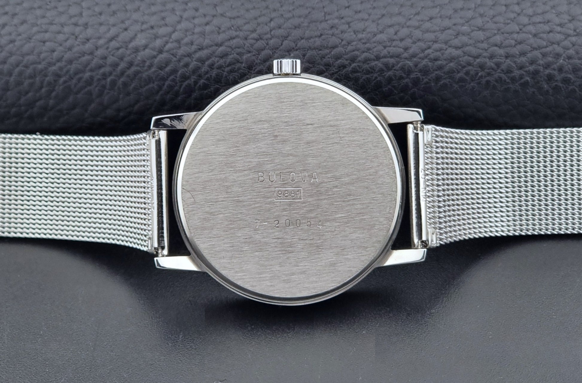 Vintage Bulova 9881 wristwatch Longchamps co-signed dial with a mesh band on a dark gray background case back view