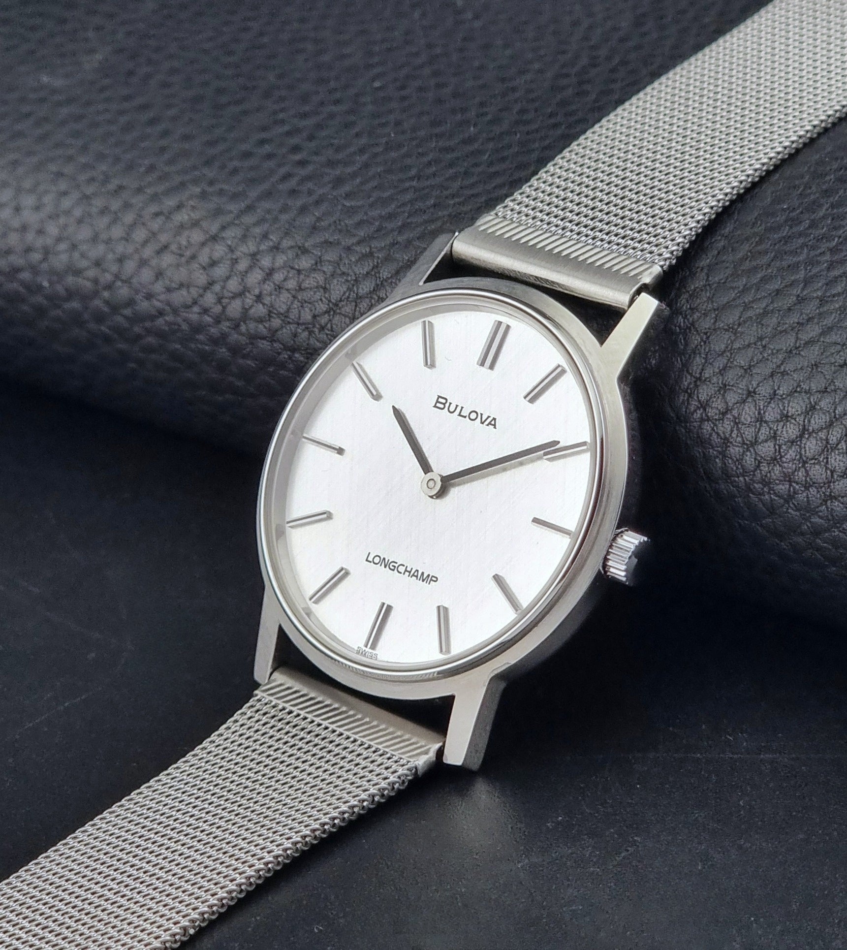 Vintage Bulova 9881 wristwatch Longchamps co-signed dial with a mesh band on a dark gray background crown view