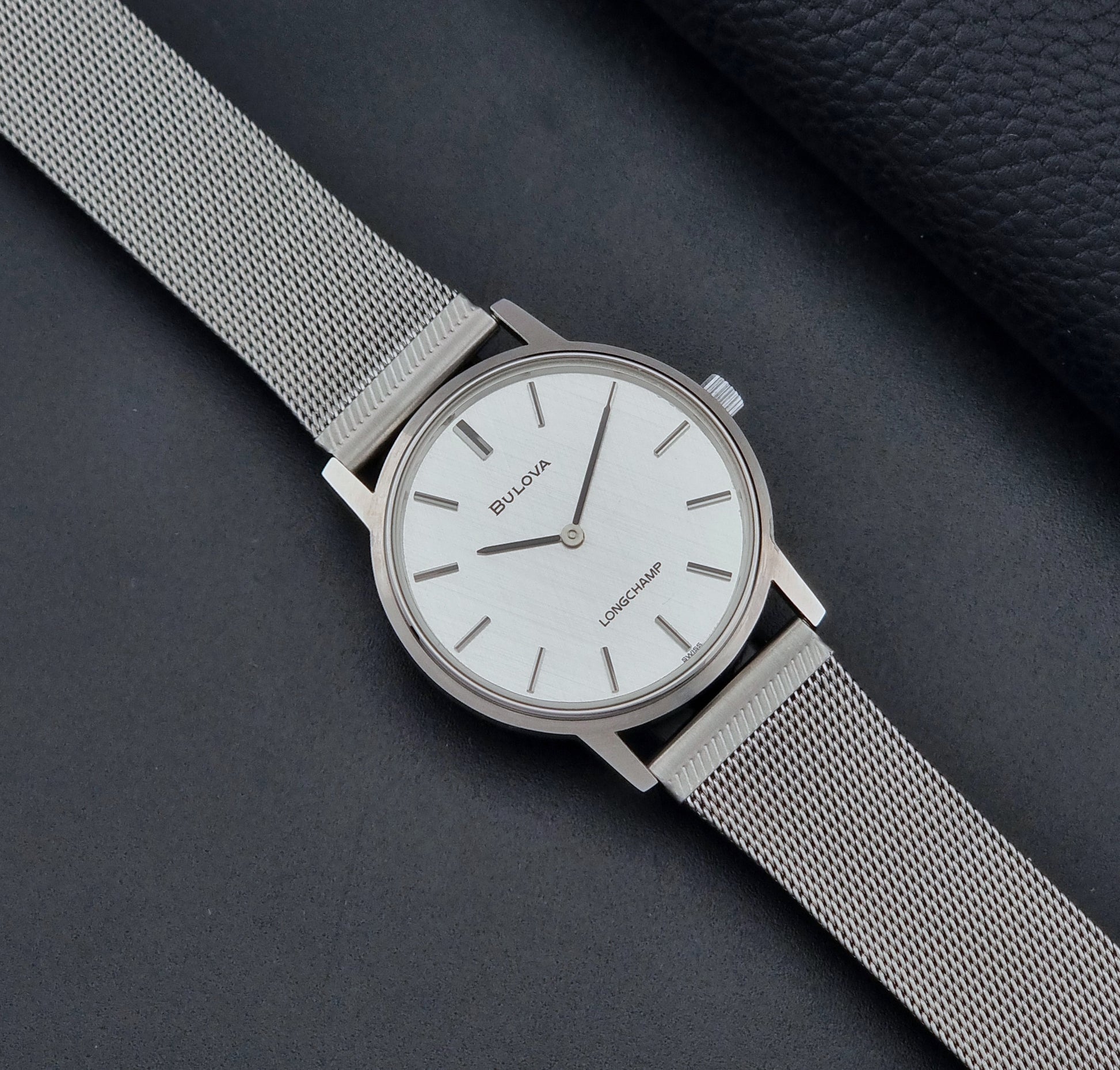 Vintage Bulova 9881 wristwatch Longchamps co-signed dial with a mesh band on a dark gray background dial