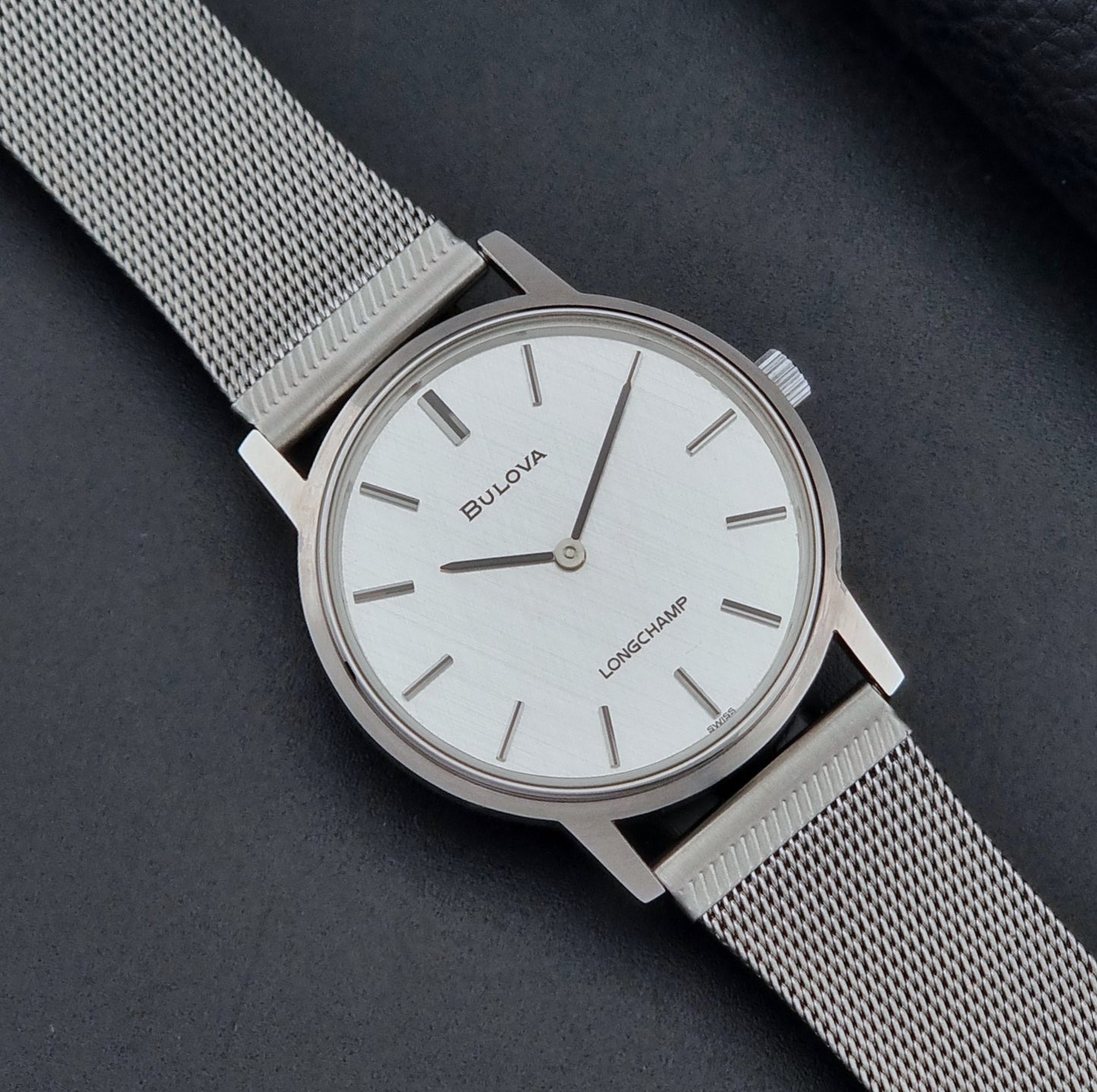 Vintage Bulova 9881 wristwatch Longchamps co-signed dial with a mesh band on a dark gray background close up dial view