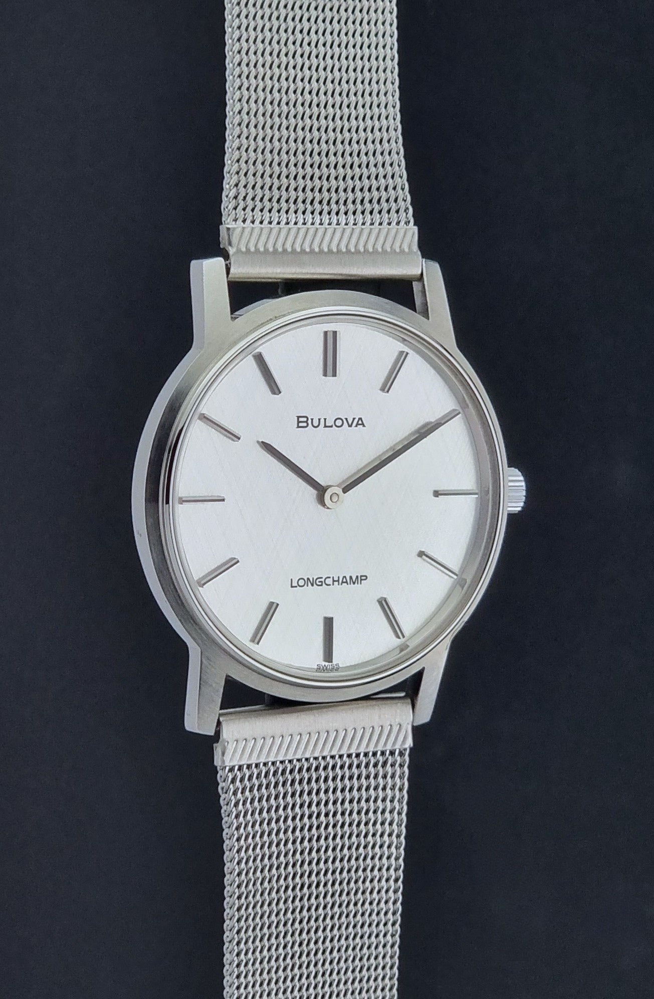 Vintage Bulova 9881 wristwatch Longchamps co-signed dial with a mesh band on a dark gray background side profile view