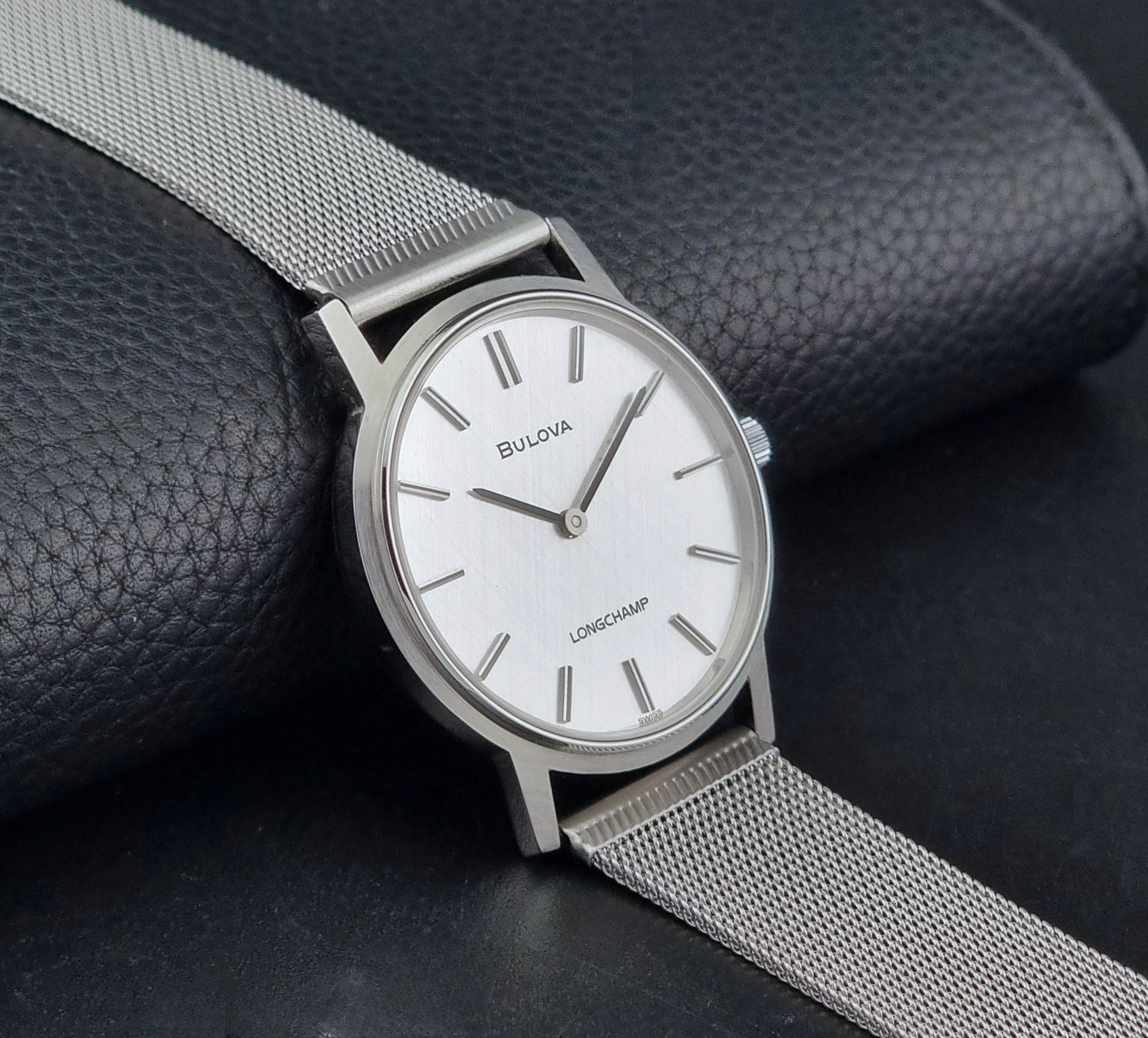 Vintage Bulova 9881 wristwatch Longchamps co-signed dial with a mesh band on a dark gray background side view