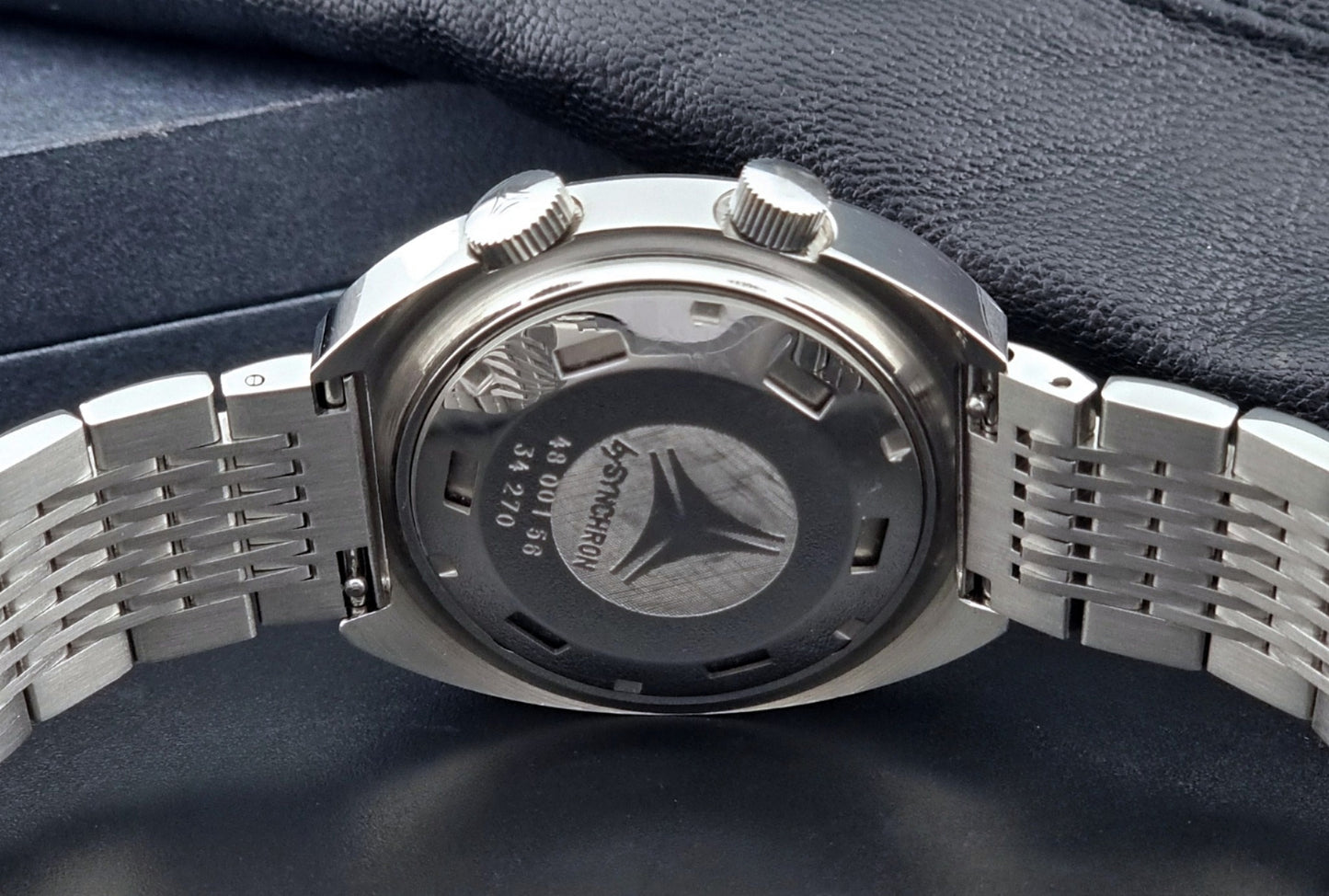 Vintage Cyma Alarm watch by Synchron a Conquistador 34270 with a detailed face on a dark surface back view