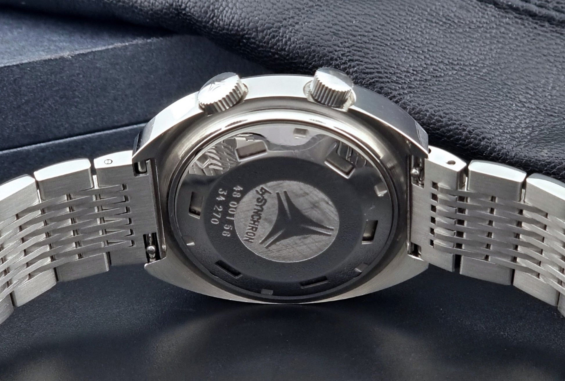 Vintage Cyma Alarm watch by Synchron a Conquistador 34270 with a detailed face on a dark surface back view