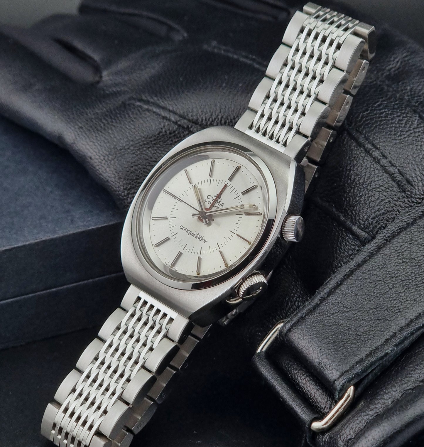 Vintage Cyma Alarm watch by Synchron a Conquistador 34270 with a detailed face on a dark surface crown view