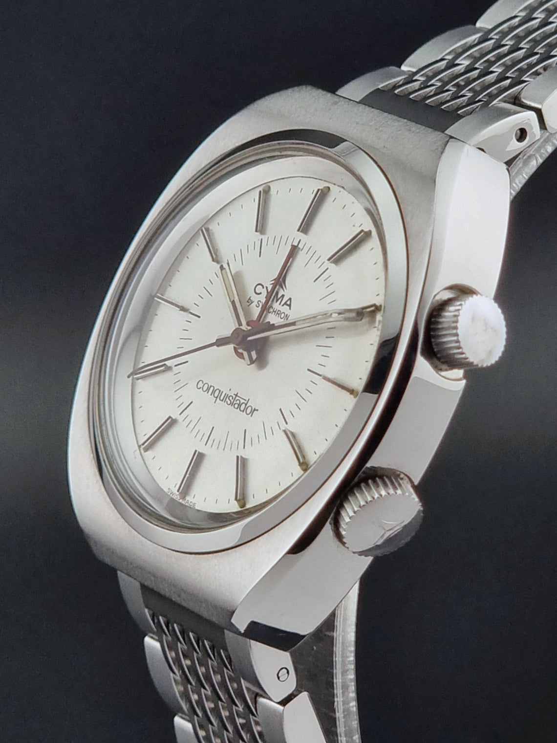Vintage Cyma Alarm watch by Synchron a Conquistador 34270 with a detailed face on a dark surface crown profile view