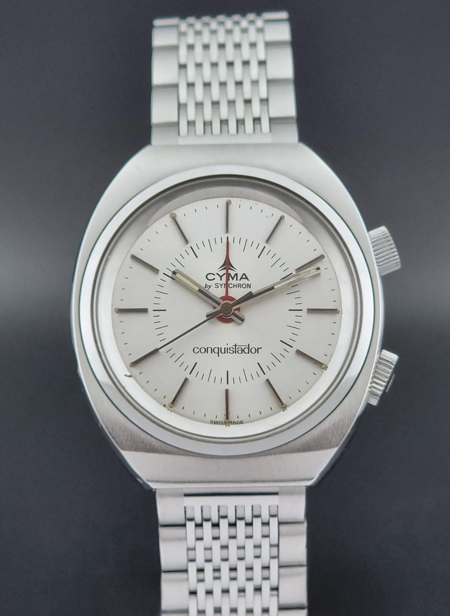 Vintage Cyma Alarm watch by Synchron a Conquistador 34270 with a detailed face on a dark surface close front view
