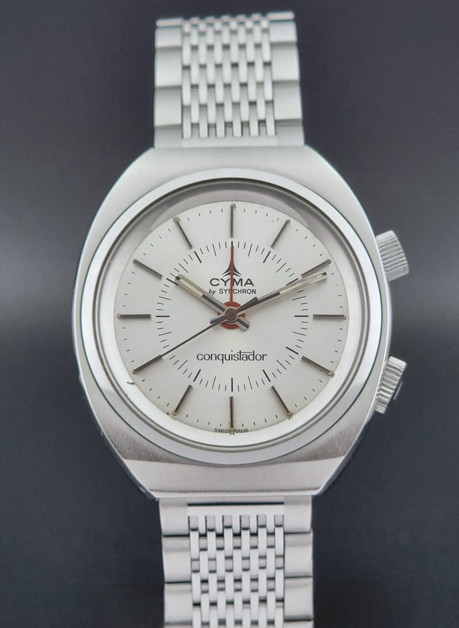 Vintage Cyma Alarm watch by Synchron a Conquistador 34270 with a detailed face on a dark surface close front view