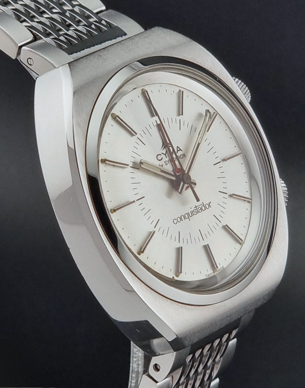 Vintage Cyma Alarm watch by Synchron a Conquistador 34270 with a detailed face on a dark surface side profile view
