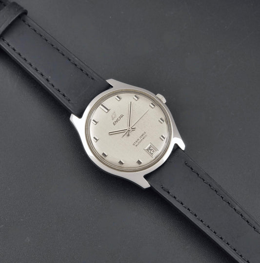 Vintage Enicar Star Jewels 144/39/14 automatic watch, front view showing the silver brushed dial, date at six and black leather strap