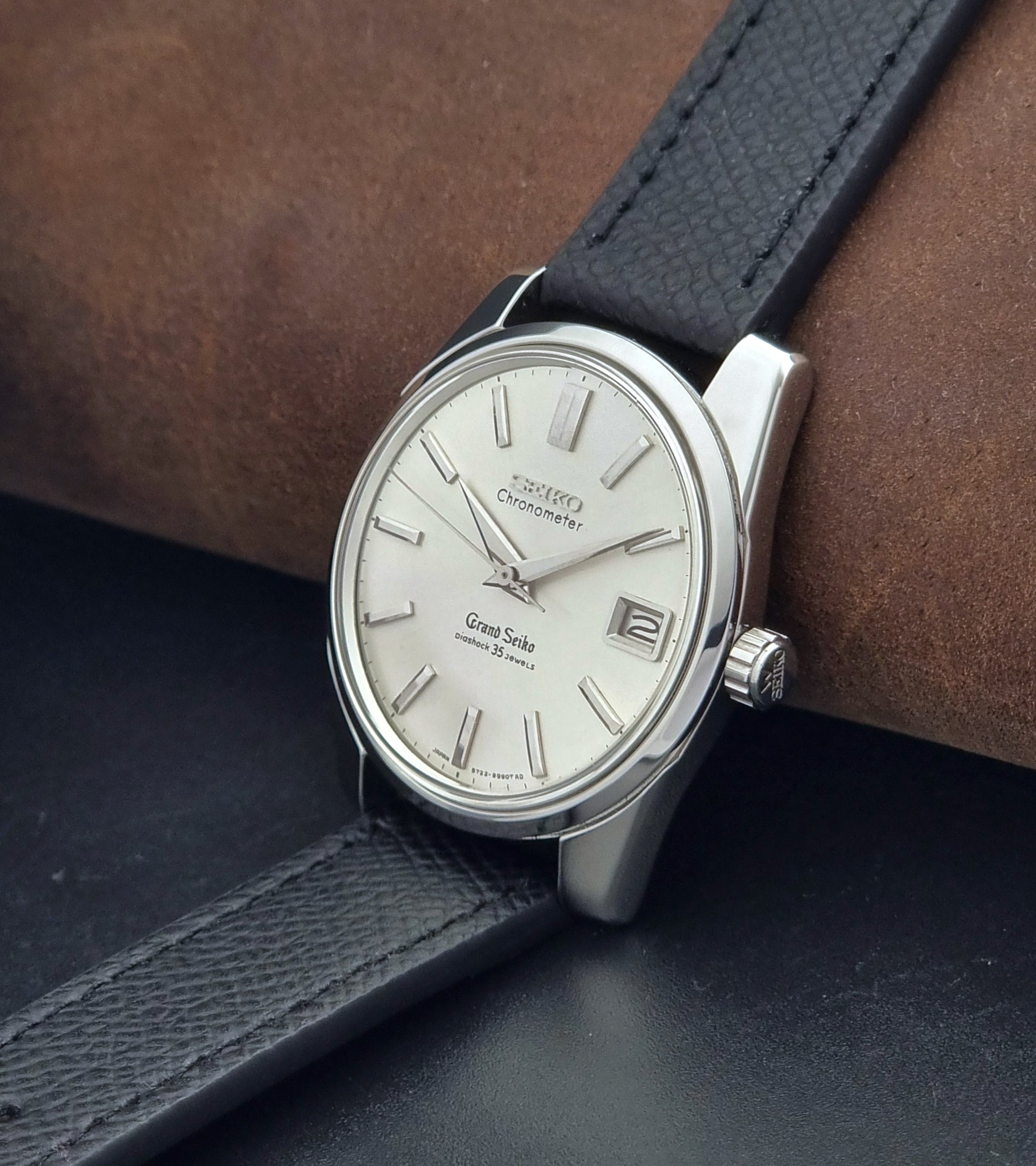 Vintage Grand Seiko Wristwatch 43999 leather strap on a gray background crown view