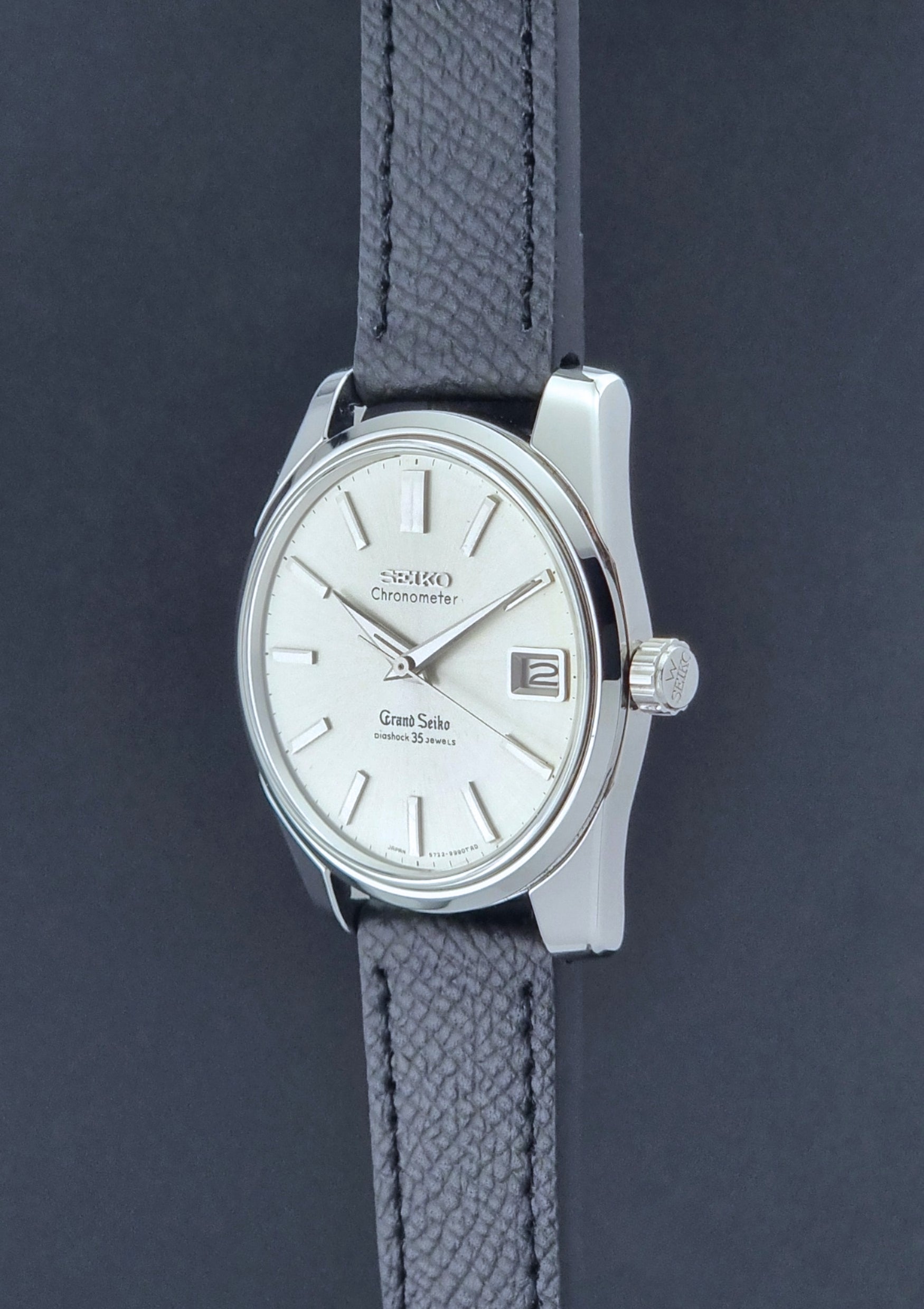 Vintage Grand Seiko Wristwatch 43999 leather strap on a gray background crown profile view