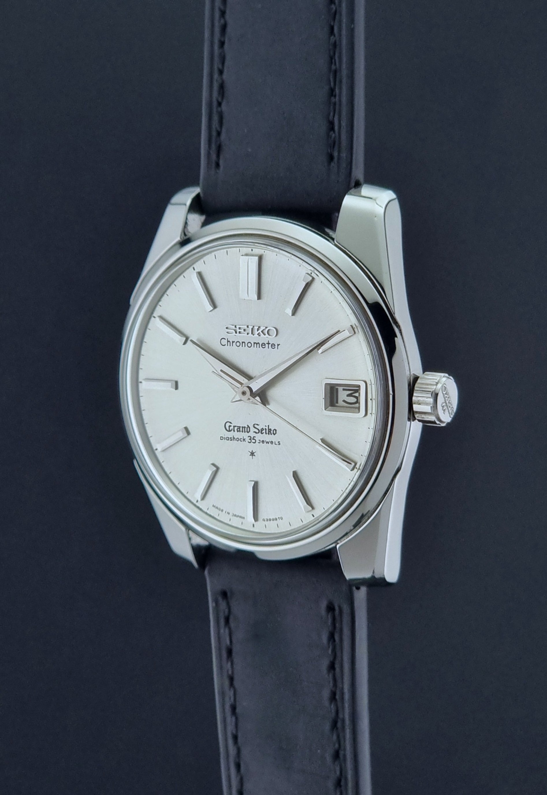 Vintage Grand Seiko Wristwatch with black leather strap on a dark background crown profile