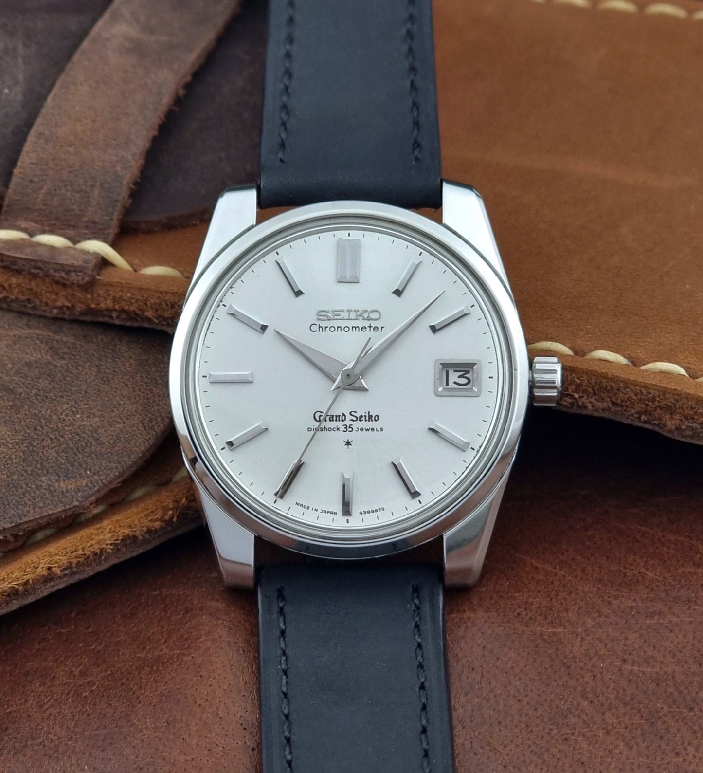 Vintage Grand Seiko Wristwatch with black leather strap on a brown background close front view