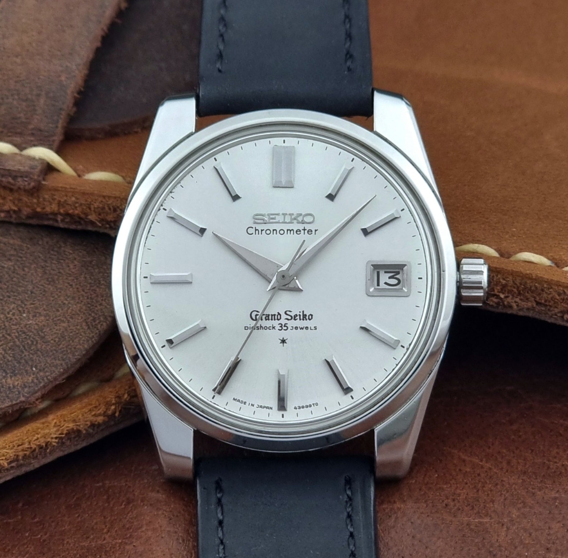 Vintage Grand Seiko Wristwatch with black leather strap on a brown background close up dial view