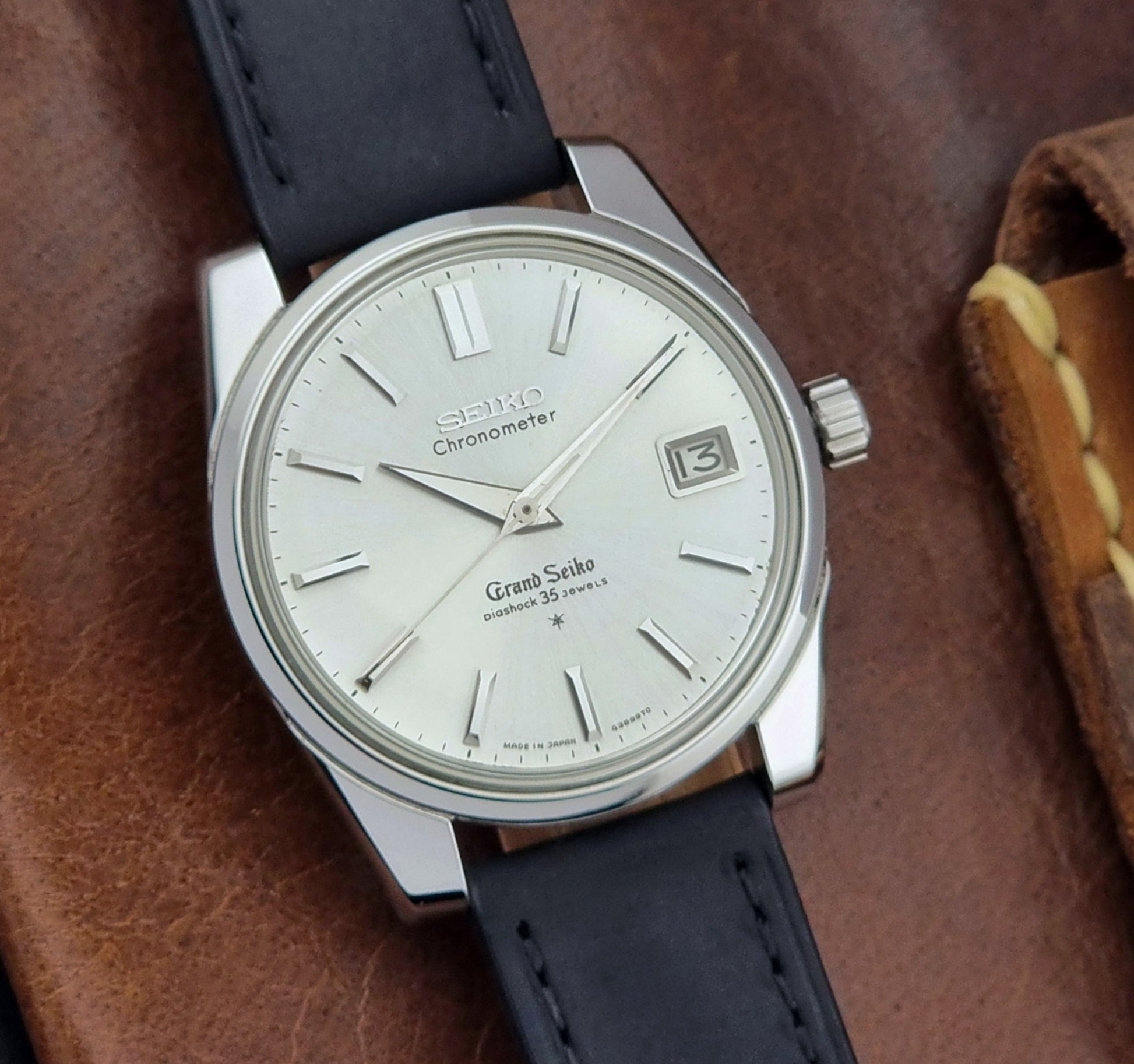 Vintage Grand Seiko Wristwatch with black leather strap on a brown background close dial view