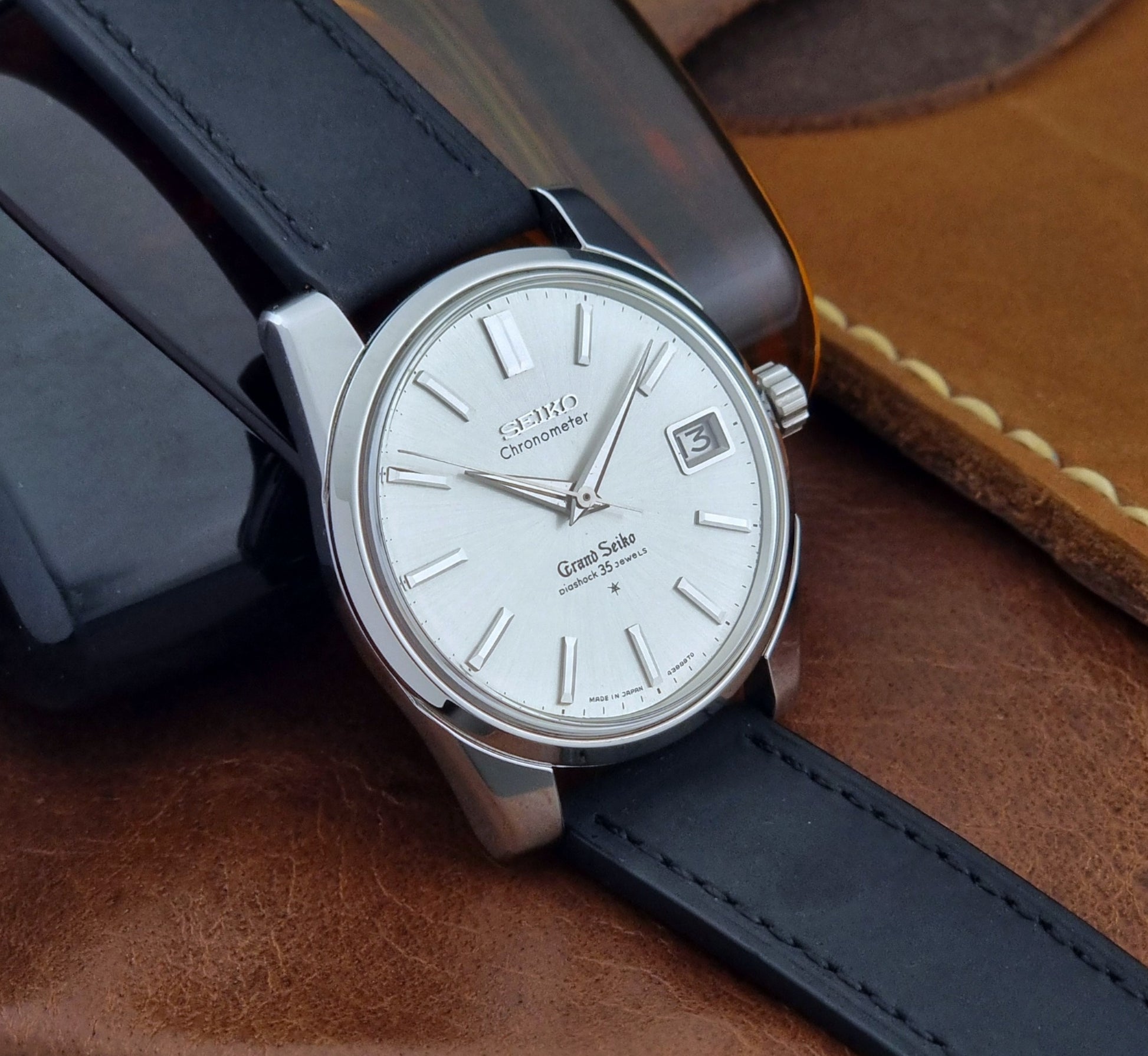 Vintage Grand Seiko Wristwatch with black leather strap on a brown background side view