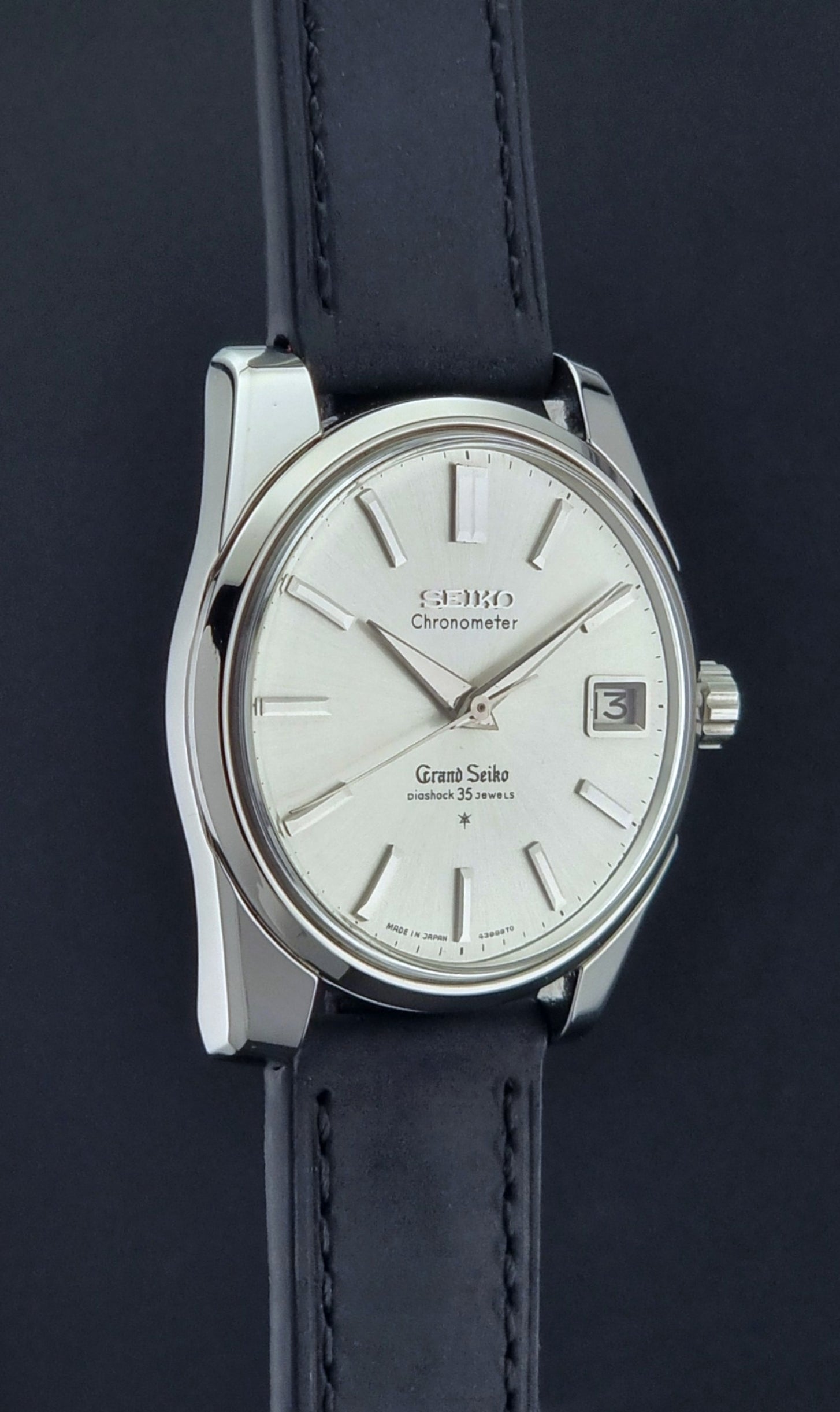 Vintage Grand Seiko Wristwatch with black leather strap on a dark background side profile