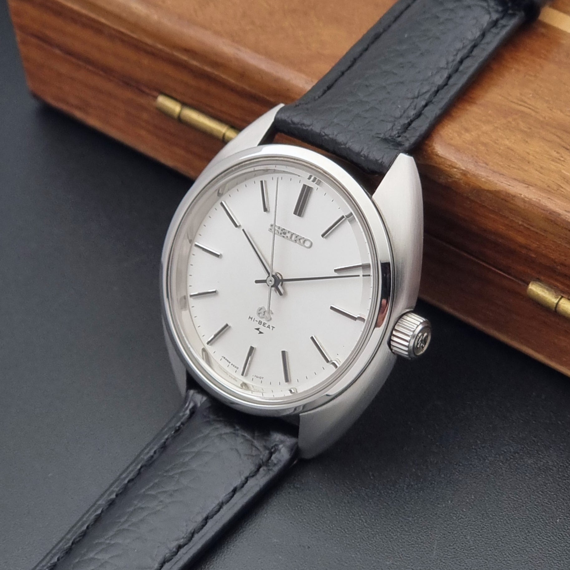 Grand Seiko watch 4520-7010 with black leather strap and silver case on a  on a dark surface crown side view