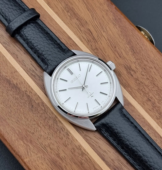 Grand Seiko watch 4520-7010 with black leather strap and silver case on a wooden surface