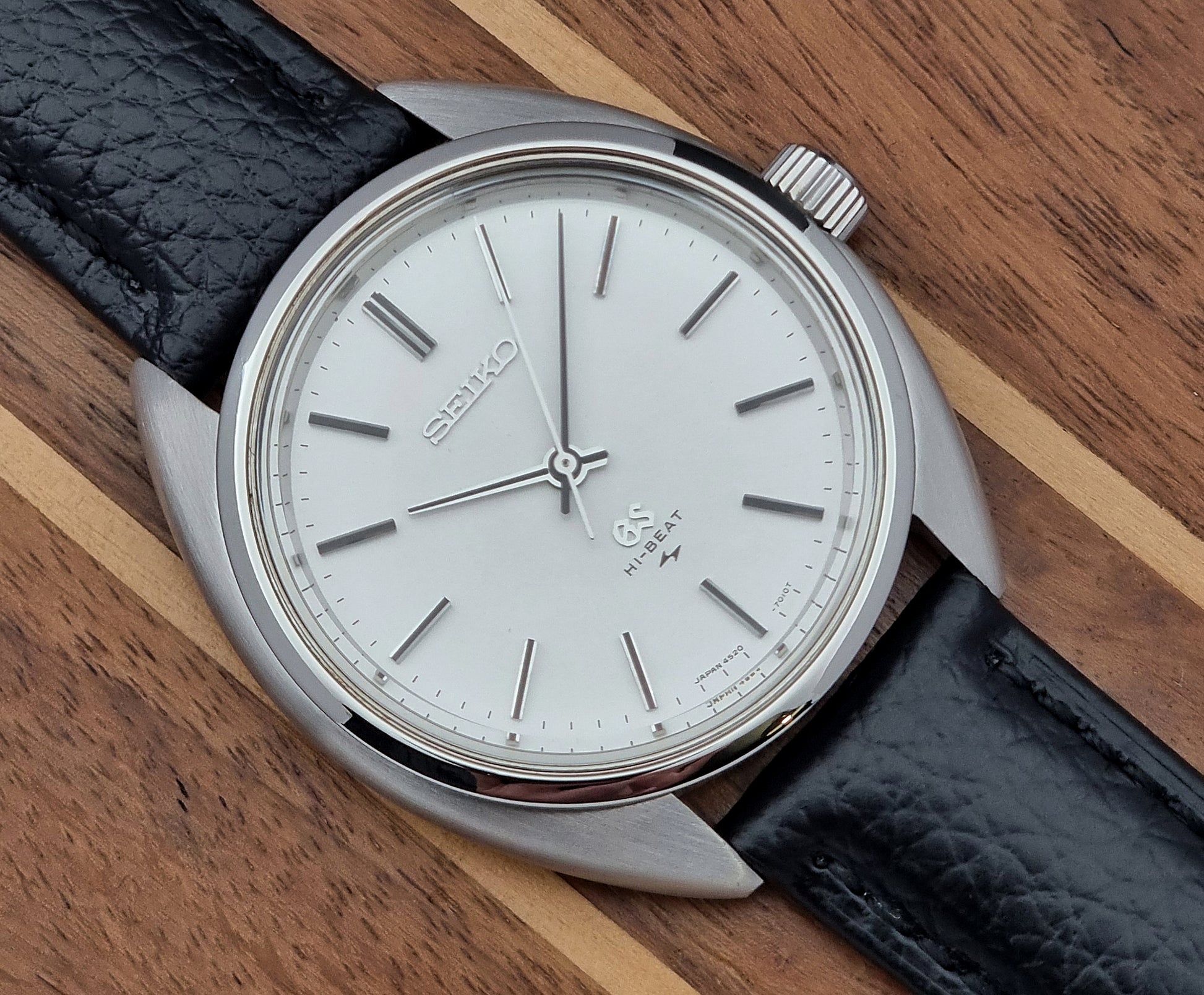 Grand Seiko watch 4520-7010 with black leather strap and silver case on a  on a wooden surface close up view