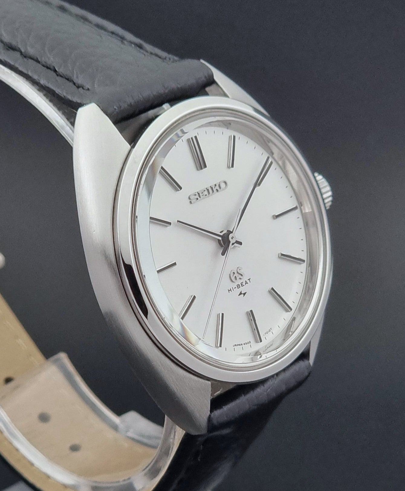 Grand Seiko watch 4520-7010 with black leather strap and silver case on a  on a dark surface profile view