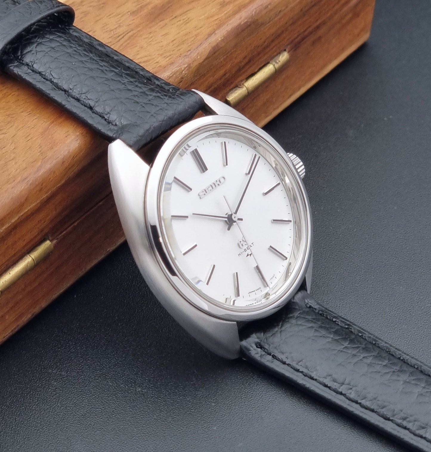 Grand Seiko watch 4520-7010 with black leather strap and silver case on a  on a dark surface  side view