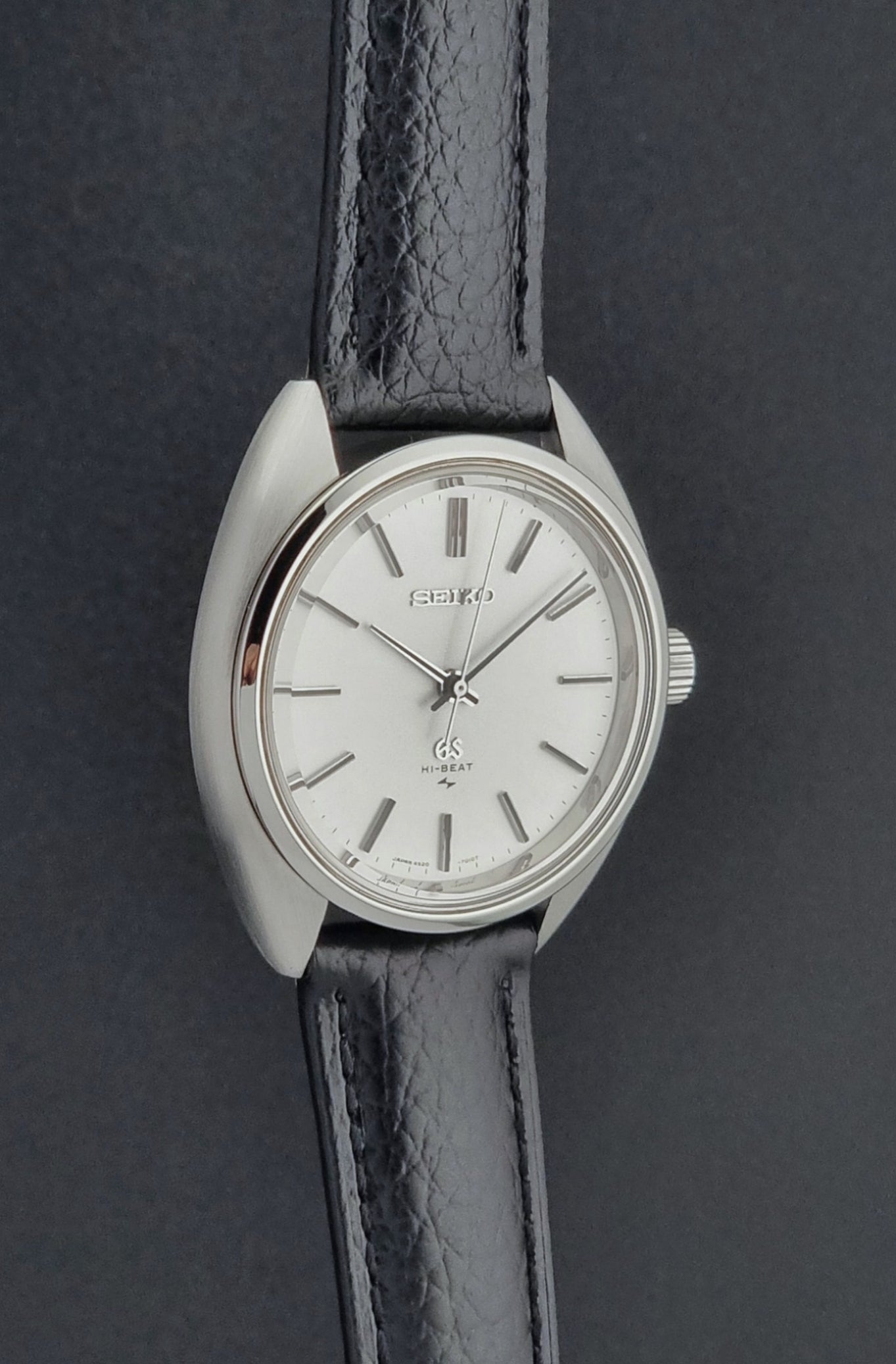 Grand Seiko watch 4520-7010 with black leather strap and silver case on a  on a dark surface side profile