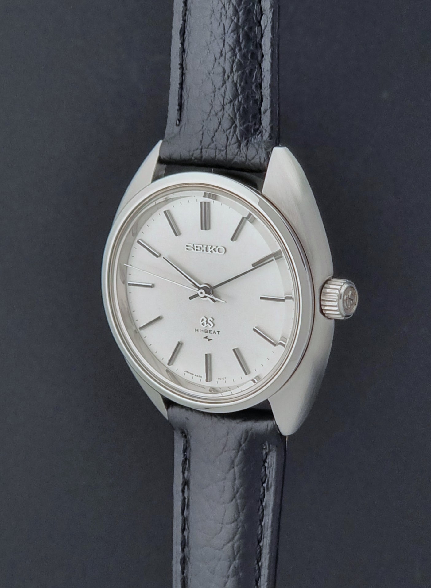 Grand Seiko watch 4520-7010 with black leather strap and silver case on a  on a dark surface crown side profile