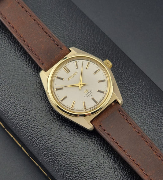 Vintage Grand Seiko Gold 4520-8000 wristwatch with a brown leather strap on a dark textured background
