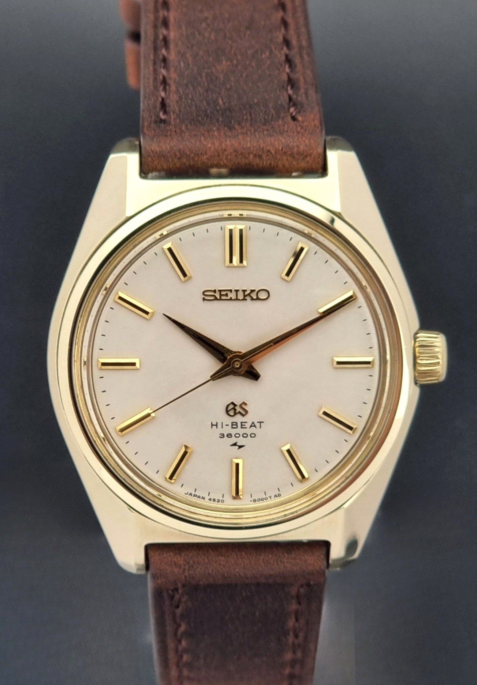 Vintage Grand Seiko 4520-8000 gold watch with brown leather strap on a dark background close up
