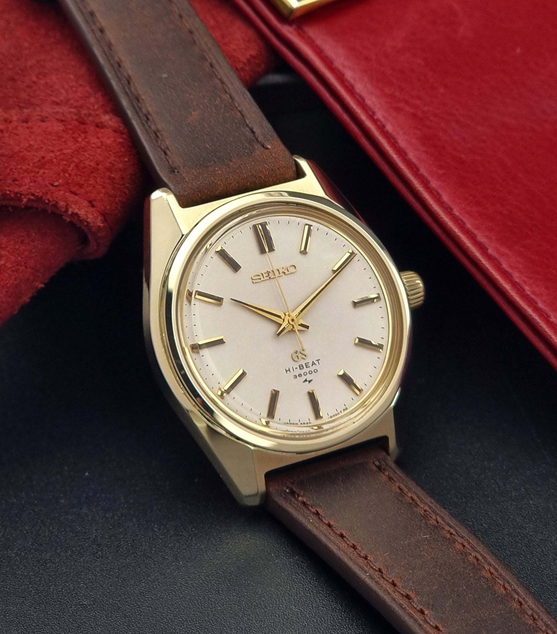 Vintage Grand Seiko 4520-8000 gold watch with brown leather strap on a dark background side view