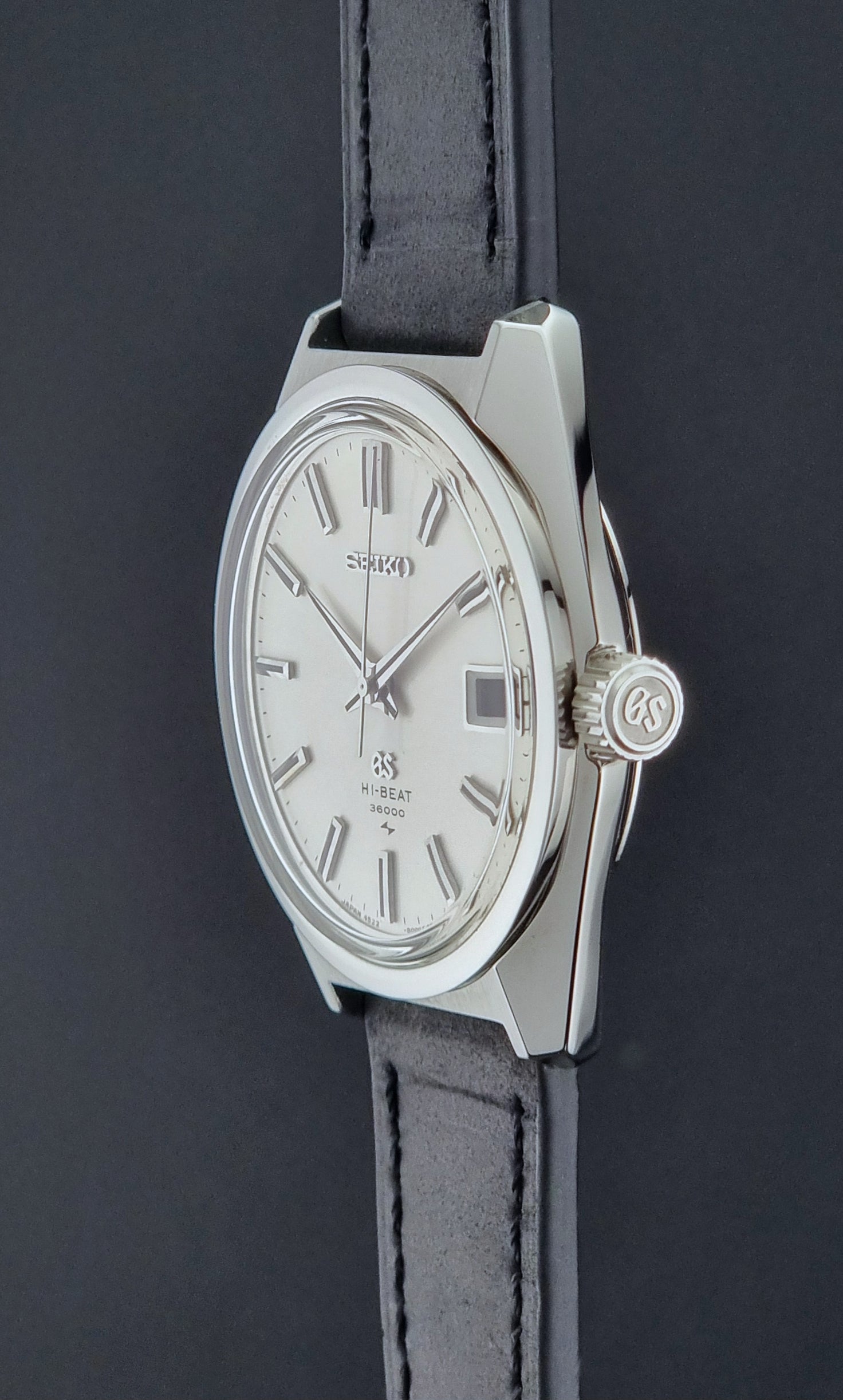 Vintage Grand Seiko 4522-8000 Wristwatch with silver case and black leather strap on a dark background