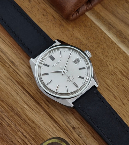 Vintage Grand Seiko watch with black leather strap on a wooden surface