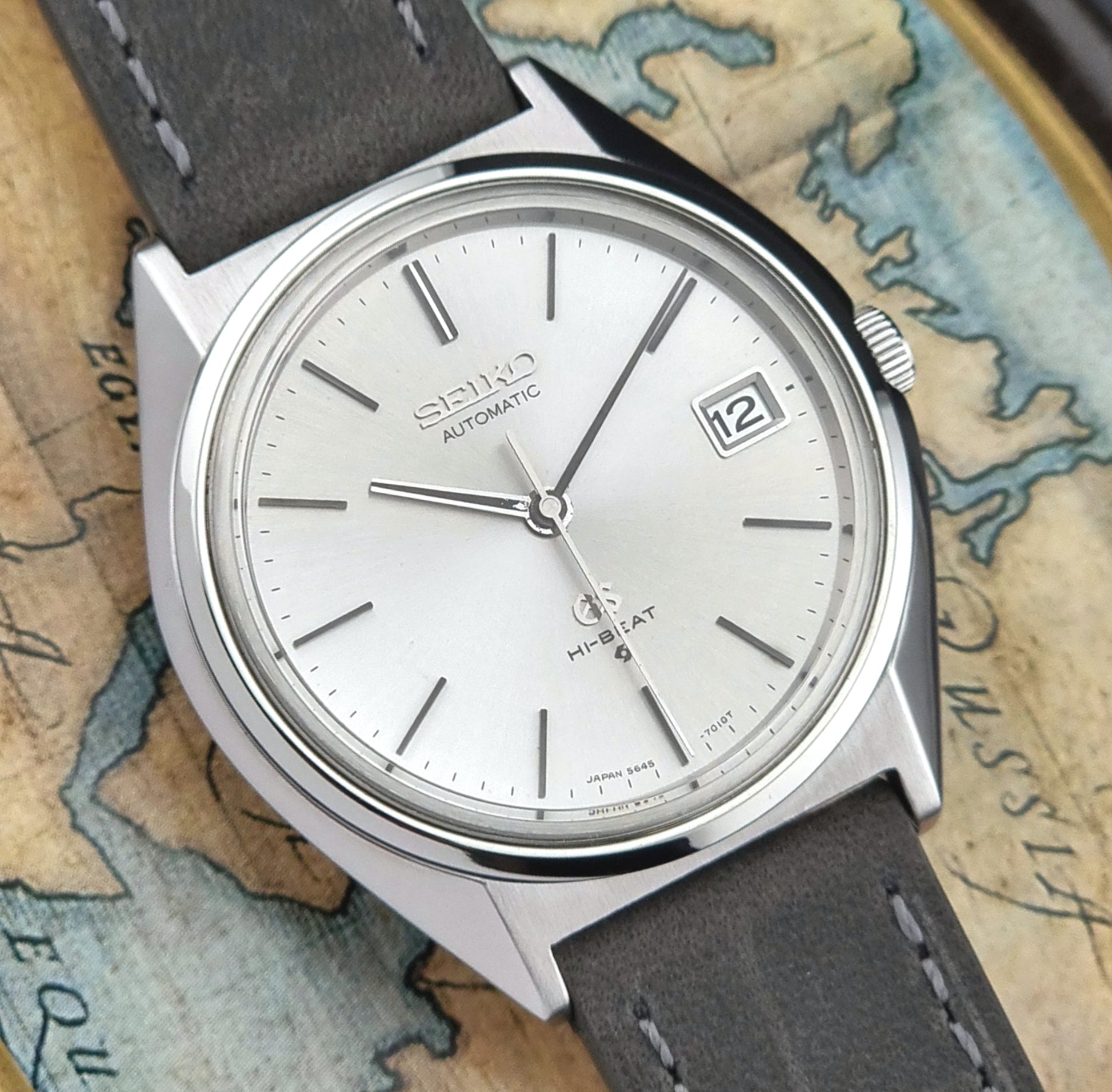 Vintage  Grand Seiko watch with gray leather strap on a world map background