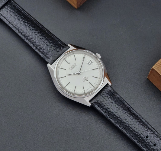 Vintage Grand Seiko Wristwatch 5645-7010 with black leather strap on a gray surface dial