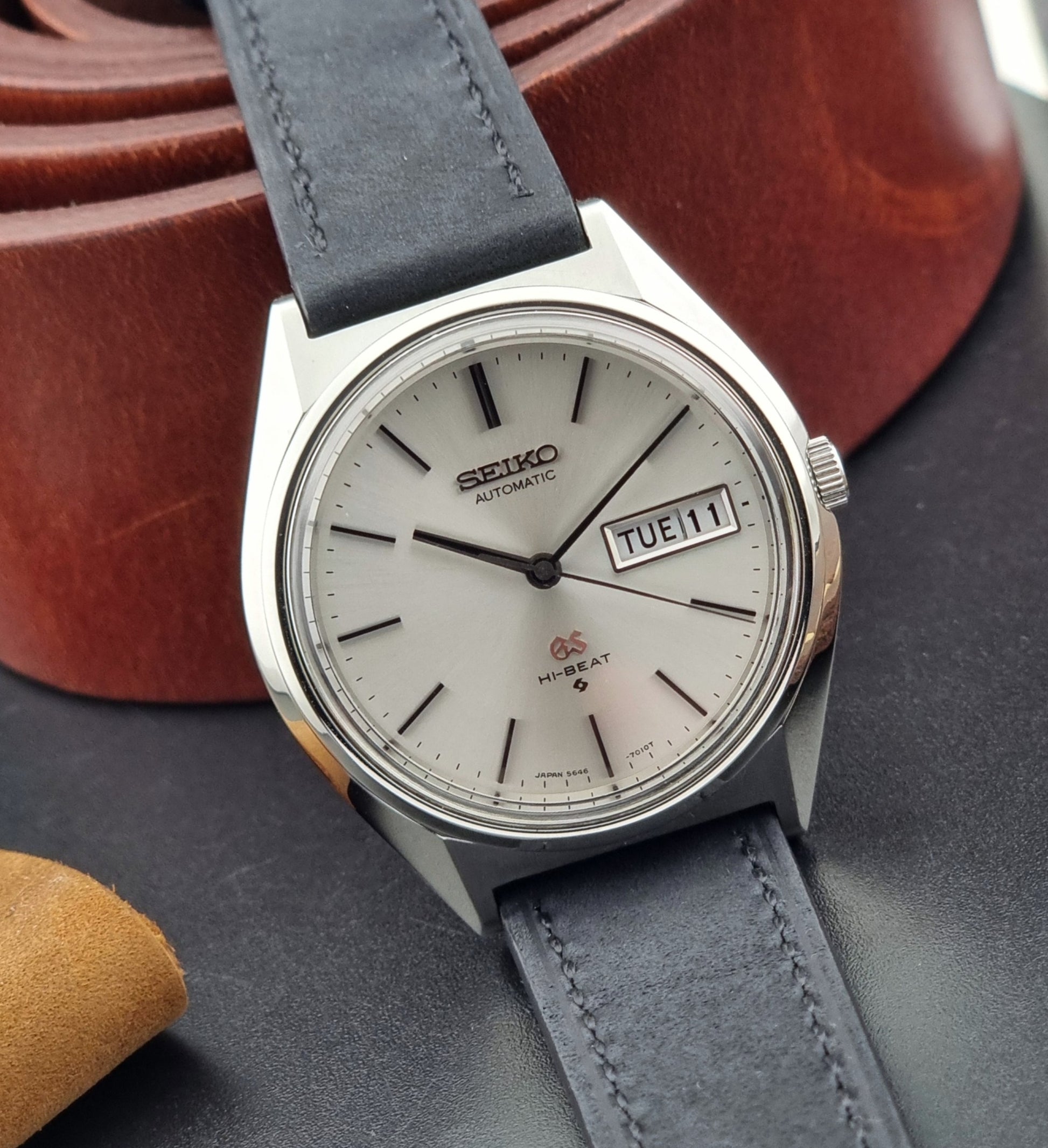 Vintage Grand Seiko watch with a black strap on a dark surface