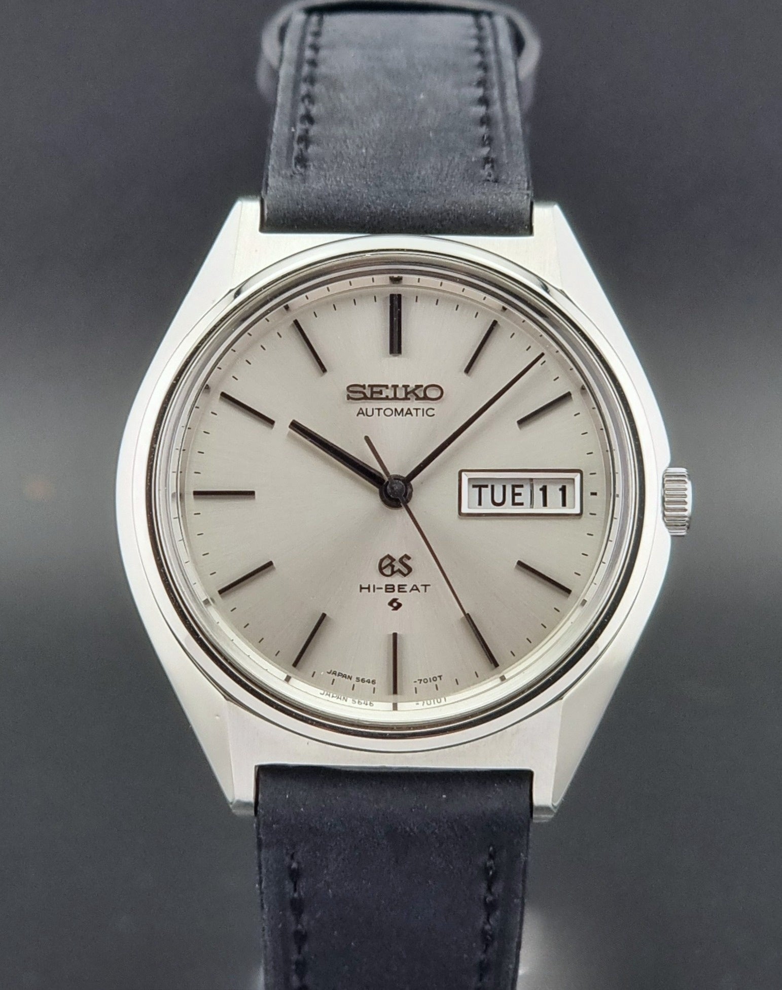 Vintage Grand Seiko watch with a dark black leather strap on a dark background