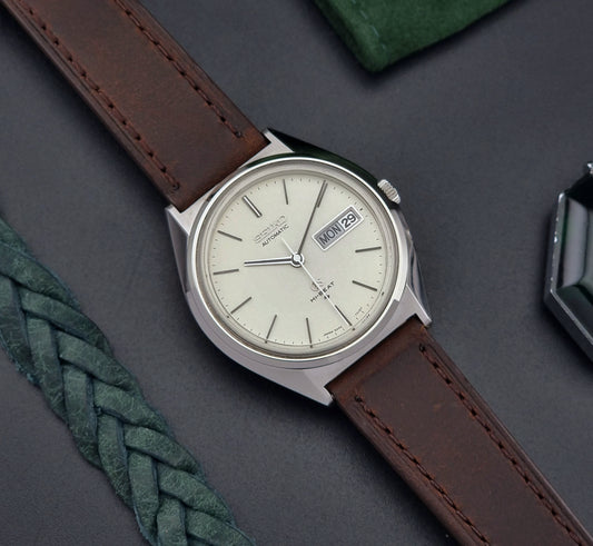 Vintage Grand Seiko Watch with brown leather strap on a gray surface