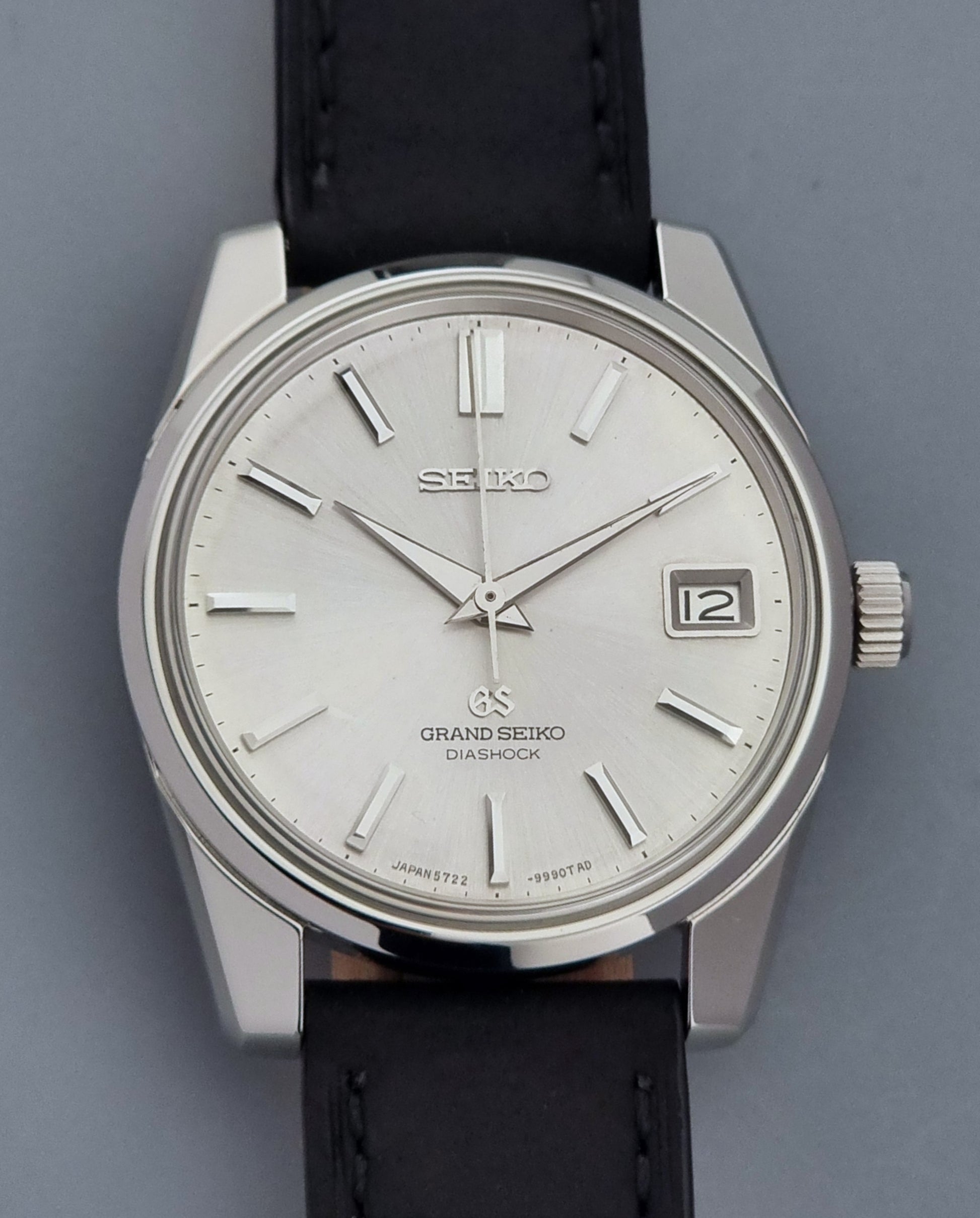 Vintage Grand Seiko Wristwatch 5722-9991 with black leather strap on a gray background close up